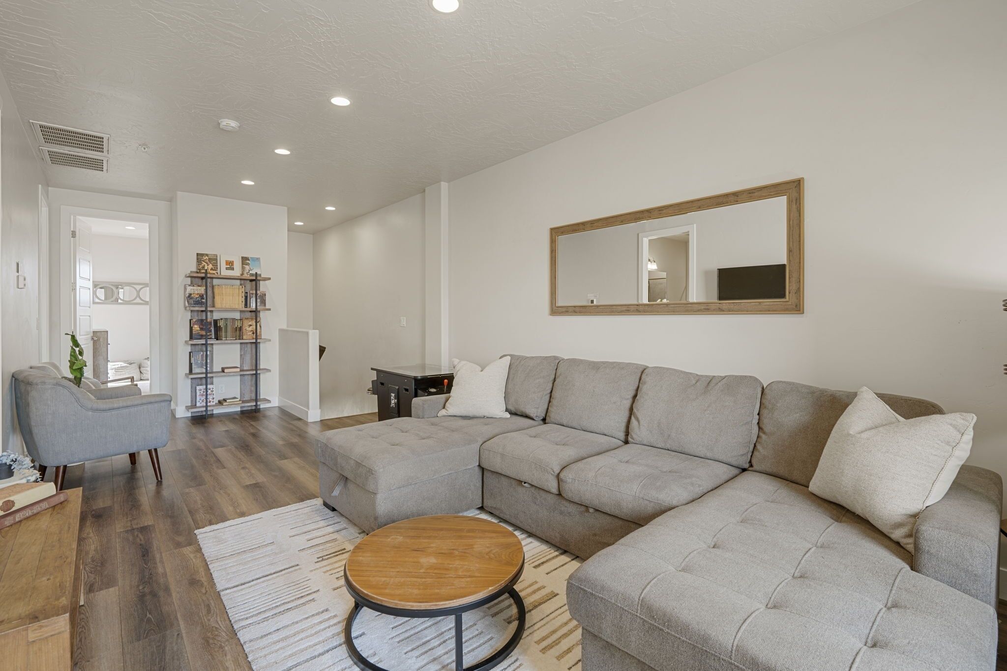 A modern living room with a sectional sofa, a round coffee table, and a bookshelf.