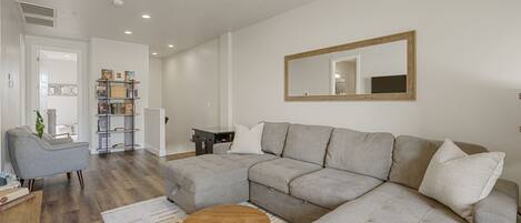 A modern living room with a sectional sofa, a round coffee table, and a bookshelf.
