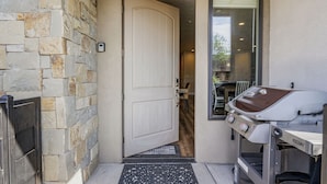 A stone wall, a white door, and a barbecue grill outside a building. - Relax In Style 4 Bedroom Townhouse (Washington)