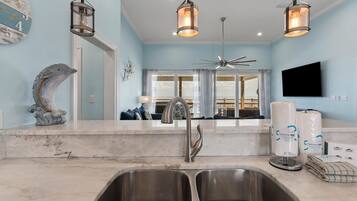 A modern kitchen with a double sink, stainless steel faucet, and pendant lighting.