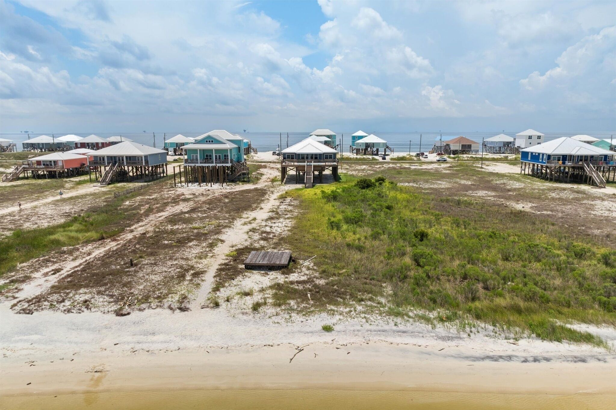 A beachside property with elevated structures, some with stairs leading up to the beach.