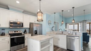 A modern kitchen with white cabinets, stainless steel appliances, and pendant lighting. - Dauphin Blue - 2824 Bienville Blvd 4 Bedroom Home (Dauphin Island)
