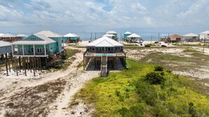 A beachfront property with multiple houses elevated on stilts, connected by walkways, and featuring a central building with a pool. - Dauphin Blue - 2824 Bienville Blvd 4 Bedroom Home (Dauphin Island)