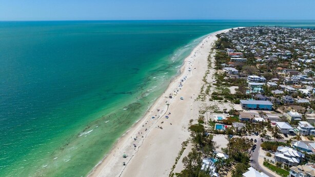 Vue aérienne d’une zone côtière avec une plage et des immeubles résidentiels.