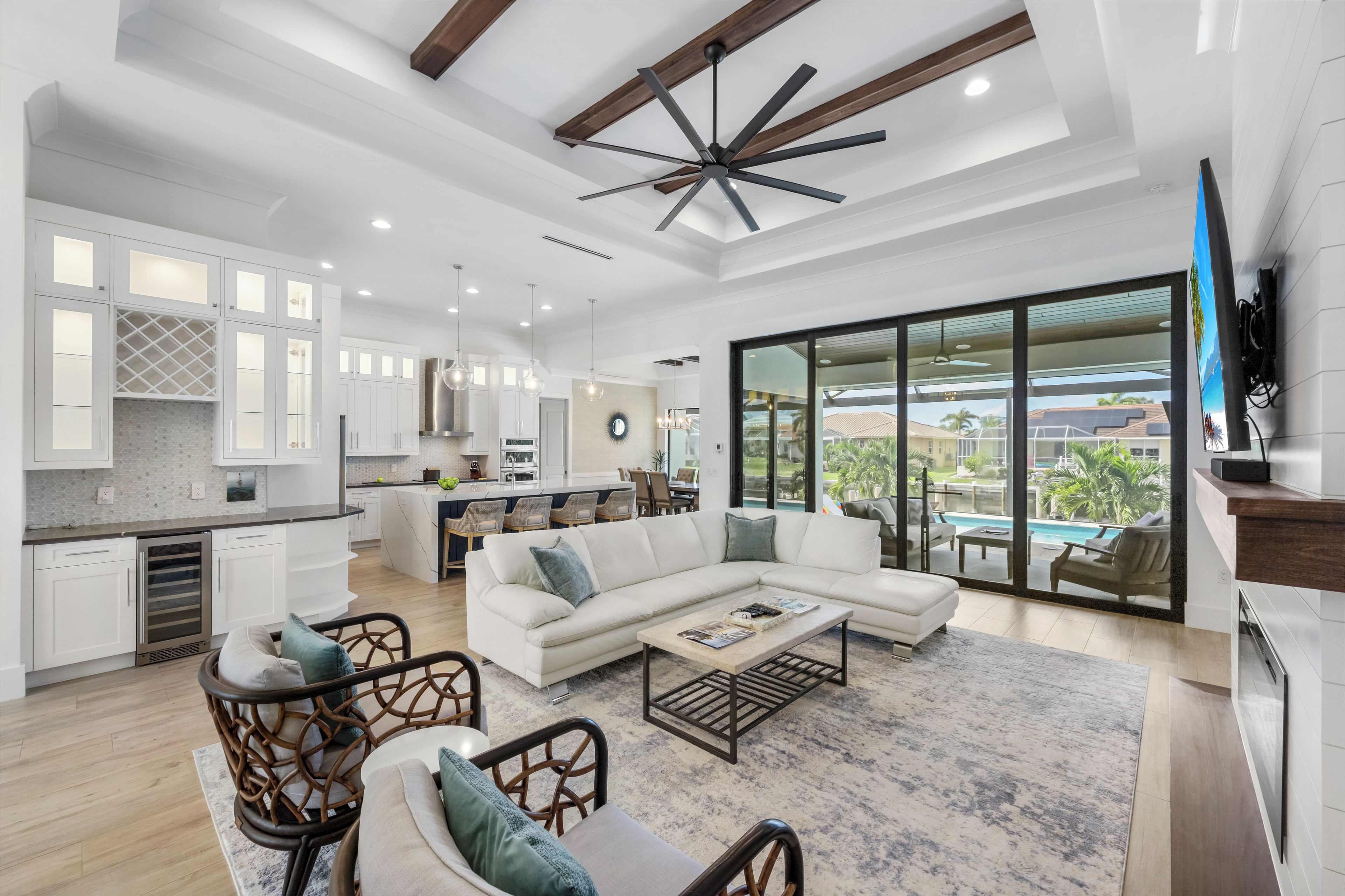 A spacious living area with a large sectional sofa, a coffee table, and a dining area with a kitchen in the background.