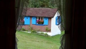 Een huis met een bruin dak, blauwe luiken en een bloembak.