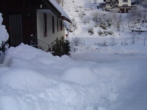 Un quartier résidentiel enneigé, avec des maisons, une clôture et une grande pile de neige.