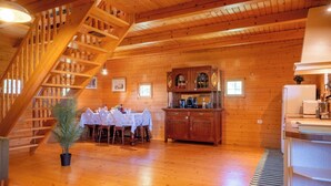 Un interior de madera con zona de comedor, una escalera y una cocina.