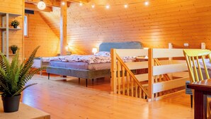 Una habitación acogedora de madera con una cama, un banco y una mesa de comedor.