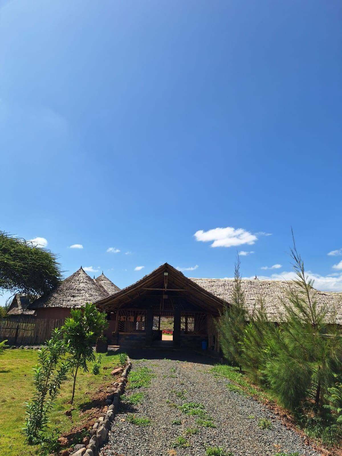 A building with a thatched roof, surrounded by a gravel path and greenery.