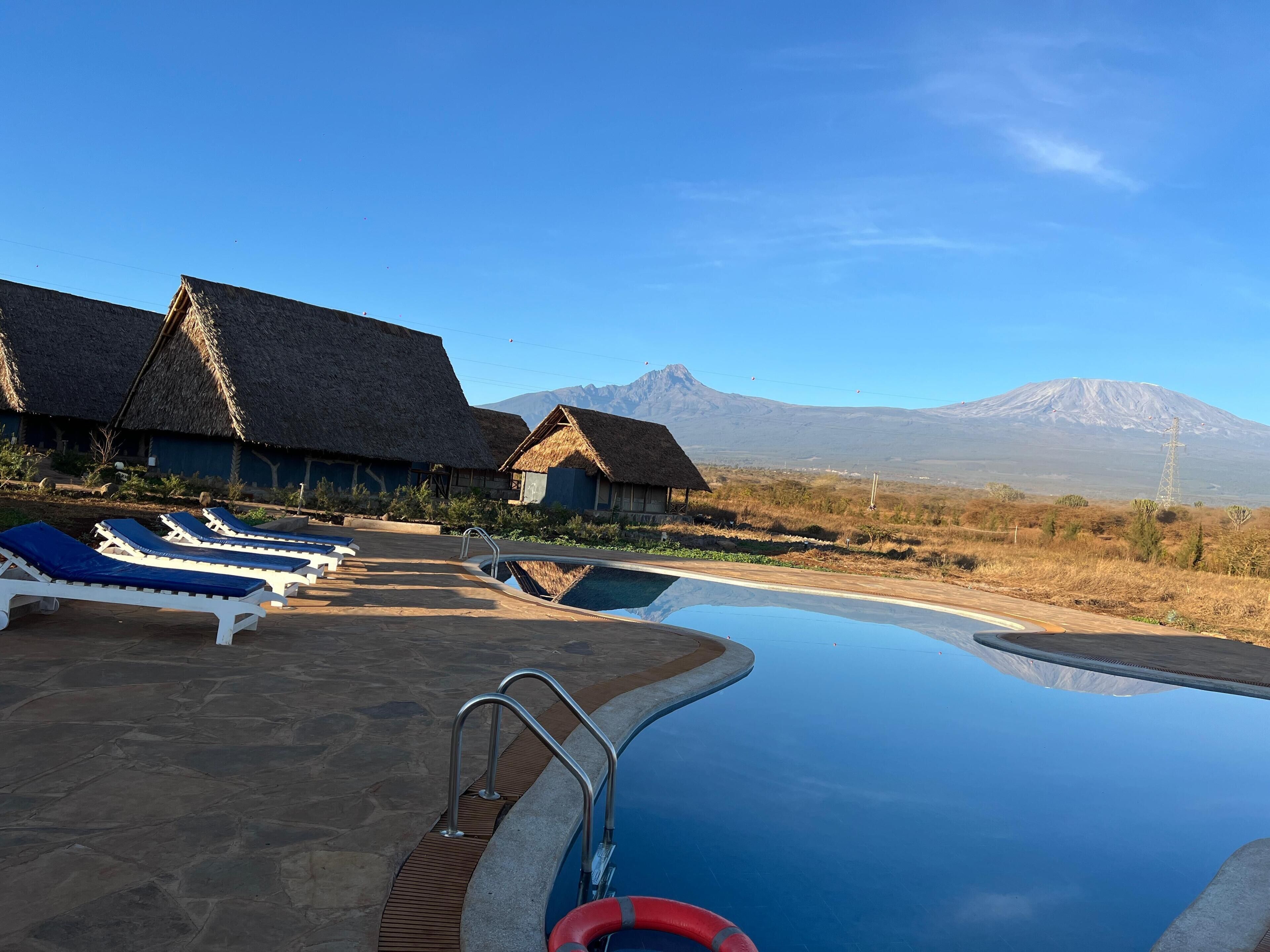 Zona de piscina con sillones de descanso y una vista despejada de una montaña al fondo.