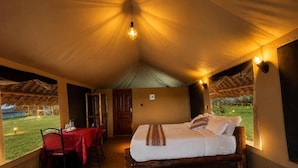 Una habitación con carpa, una cama, una mesa de comedor y sillas.