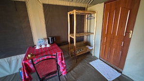 Una habitación con una mesa dispuesta para el desayuno, una silla, un estante de madera con perchas y una puerta.