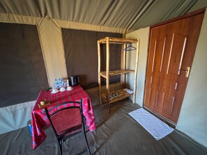 A room with a table set for breakfast, a chair, a wooden shelf with hangers, and a door.
