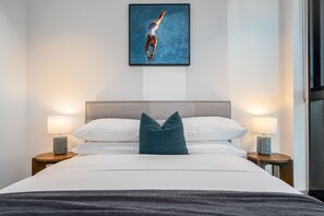 A hotel room with a bed, two bedside lamps, a framed artwork above the bed, and a window to the right. - Lvl 63 Sunset Skyline Luxe Apartment CBD Parking (Melbourne)