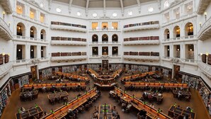 Una biblioteca de varios niveles con una zona central de lectura rodeada de estanterías.