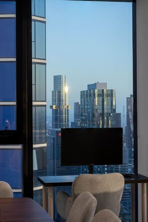 A modern office space with a large window overlooking a cityscape. - Lvl 63 Sunset Skyline Luxe Apartment CBD Parking (Melbourne)