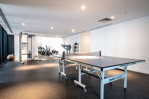 A spacious indoor area with a ping pong table, exercise equipment, and a mirrored wall.