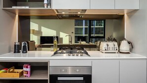 Una cocina moderna con estufa a gas, tostadora y hervidor, horno empotrado y ventana con vista a la ciudad.