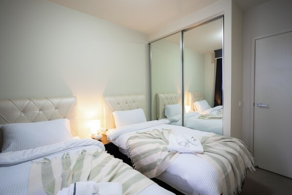A hotel room with two beds, a large mirror, and a wardrobe.