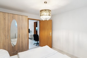 A bedroom with a wooden wardrobe, a mirror, a bed, a desk, and a chair. - Holiday Apartment 'Knittlingen' Dishwasher, Washing Machine, FREE Wifi, Private Parking (Knittlingen)