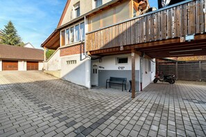 A residential building with a wooden balcony, a paved driveway, and a parked scooter. - Holiday Apartment 'Knittlingen' Dishwasher, Washing Machine, FREE Wifi, Private Parking (Knittlingen)