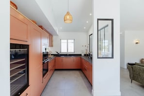 A modern kitchen with peach-colored cabinets, a black countertop, and a large window.