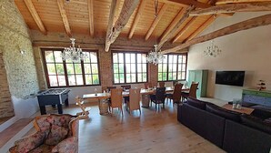 Un'ampia zona giorno con soffitto in legno, un tavolo da pranzo con sedie, un divano e un televisore a parete.