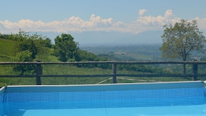 Una piscina con vista su un paesaggio verde e montagne in lontananza.