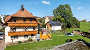 A two-story house with a sloped roof, a balcony, and a solar panel on the roof. - Ferienwohnung Schäfer – Nature, Comfort & Relaxation in the Black Forest (Freudenstadt)