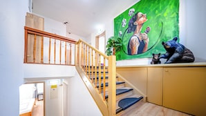 A staircase with wooden railings leading to a room with a bed and a desk.