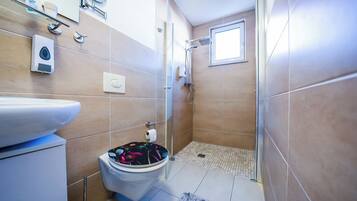 A bathroom with a toilet, bidet, and shower.