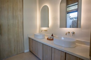 A bathroom with two sinks, wooden cabinets, and a large mirror.