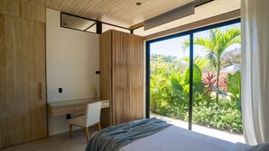 Ein modernes Schlafzimmer mit großem Fenster, einem Holztisch und einem Bett.