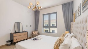 Un dormitorio moderno con una cama grande, un aparador, un espejo y una ventana con cortinas.