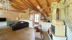 A spacious living area with a wooden ceiling, a stone wall, a fireplace, and a sofa. - Family-friendly oasis of well-being with a great pool - Il Roseto II (Piemonte)