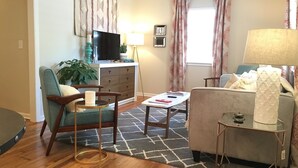 A living room with a sofa, armchairs, a coffee table, a TV, and a lamp. - Charming 4BR Duplex Home |  5&6 (Kansas City)