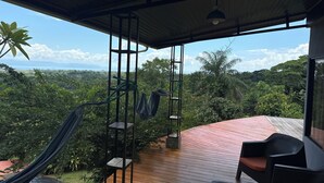 A wooden deck with a hammock, chairs, and a view of a lush landscape. - Welcome to Osa Views we’re really happy to have you in our house . (Provincia de Puntarenas)