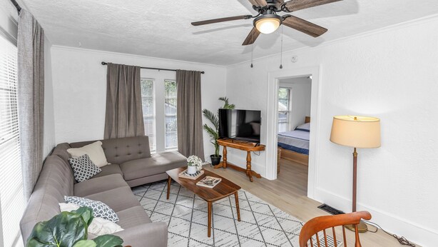 Ein modernes Wohnzimmer mit einer Couch, einem Couchtisch und einem Deckenventilator.
