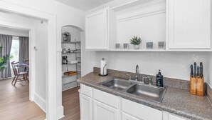 Eine moderne Küche mit weißen Schränken, Granit Arbeitsplatten, einer Spüle und einer Kaffeemaschine.