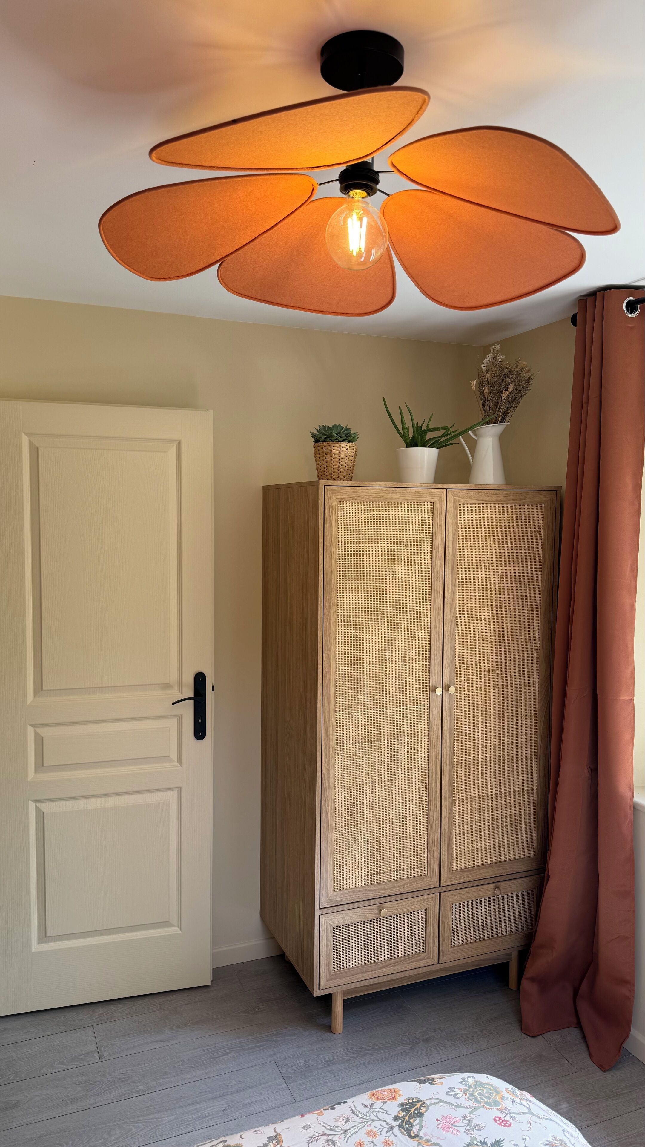 A room with a wooden wardrobe, a door, a ceiling fan, and a curtain.