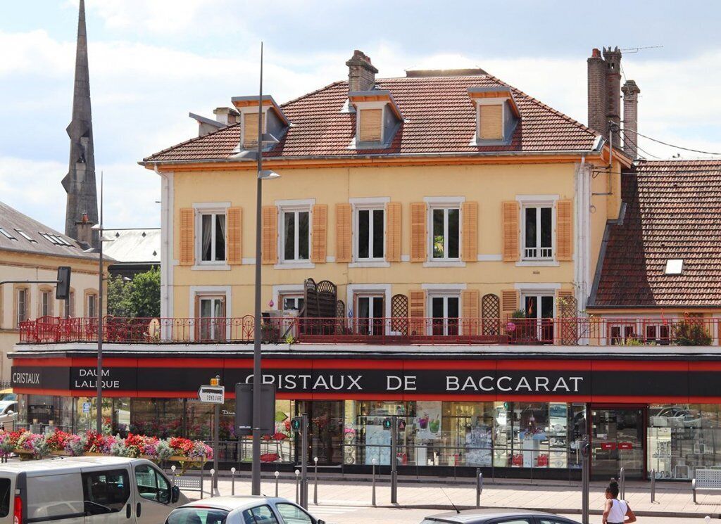 Un bâtiment doté d’une devanture portant l’inscription « PISTAUX DE BACCARAT » et devant lequel est garé un fourgon bien visible.