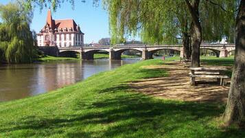 A riverside park with a historic building, a stone bridge, and a picnic area.