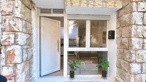 A stone building entrance with a white door, a window, and two potted plants. - Valdecanillas 1 bedroom (Madrid)