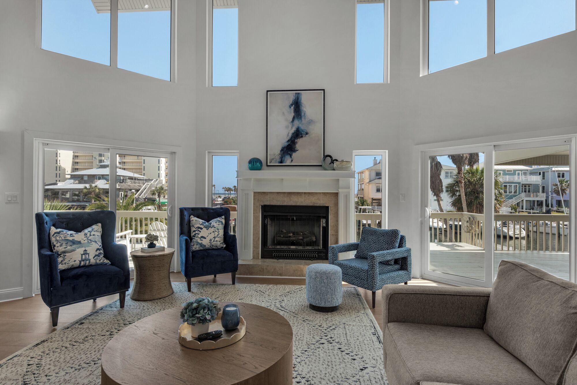 A spacious living room with a fireplace, large windows, and a view of the ocean.
