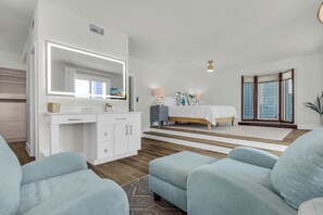 Ein modernes Schlafzimmer mit einem großen Bett, einem Schminktisch mit Spiegel und einer Sitzecke mit zwei Sofas.