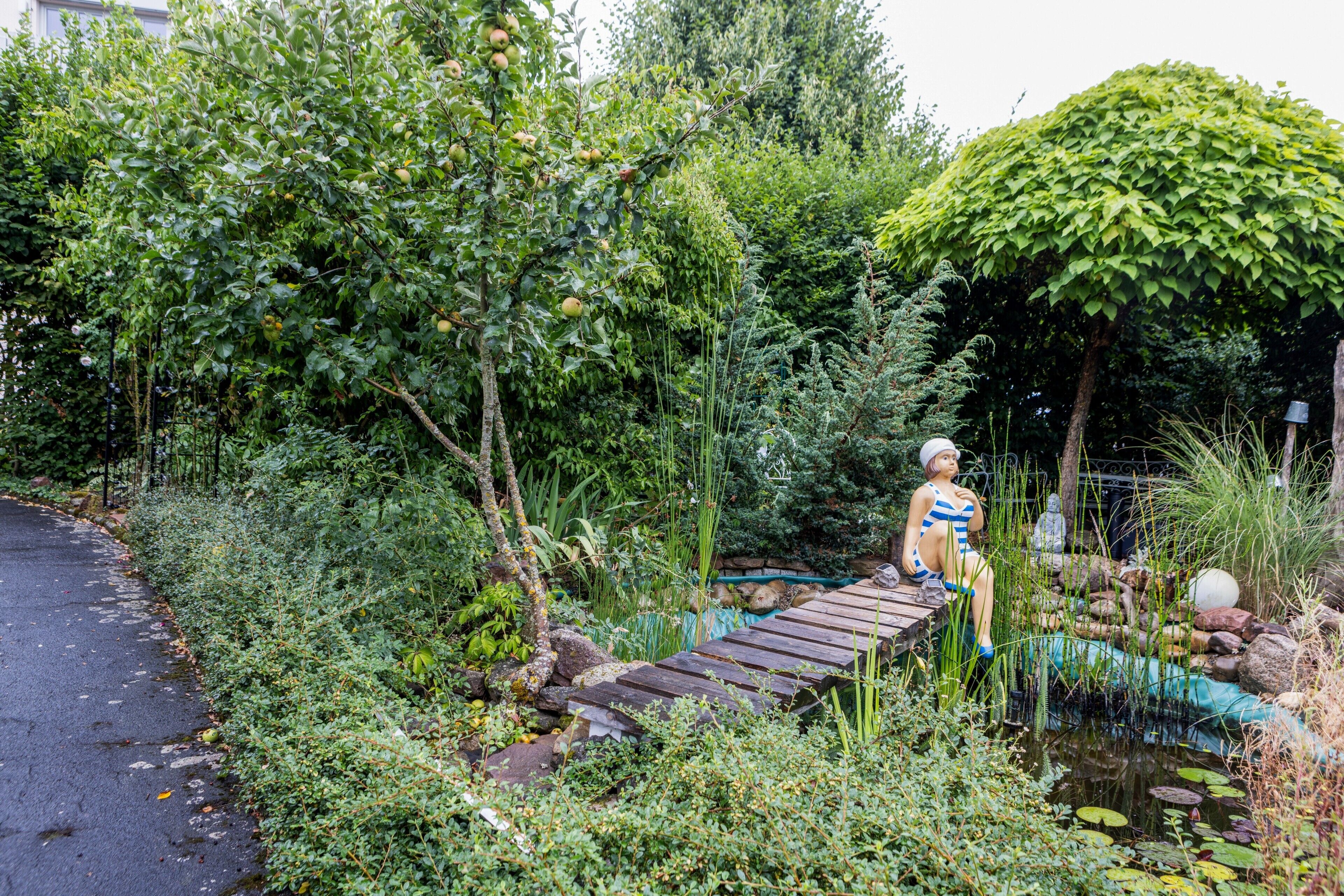 Ein Garten mit einer Holzbrücke, einem Teich und einer Statue.