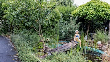 Ein Garten mit einer Holzbrücke, einem Teich und einer Statue.