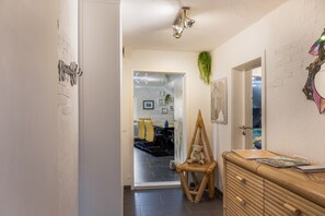 A hallway with a wooden dresser, a chair, and a hanging plant.