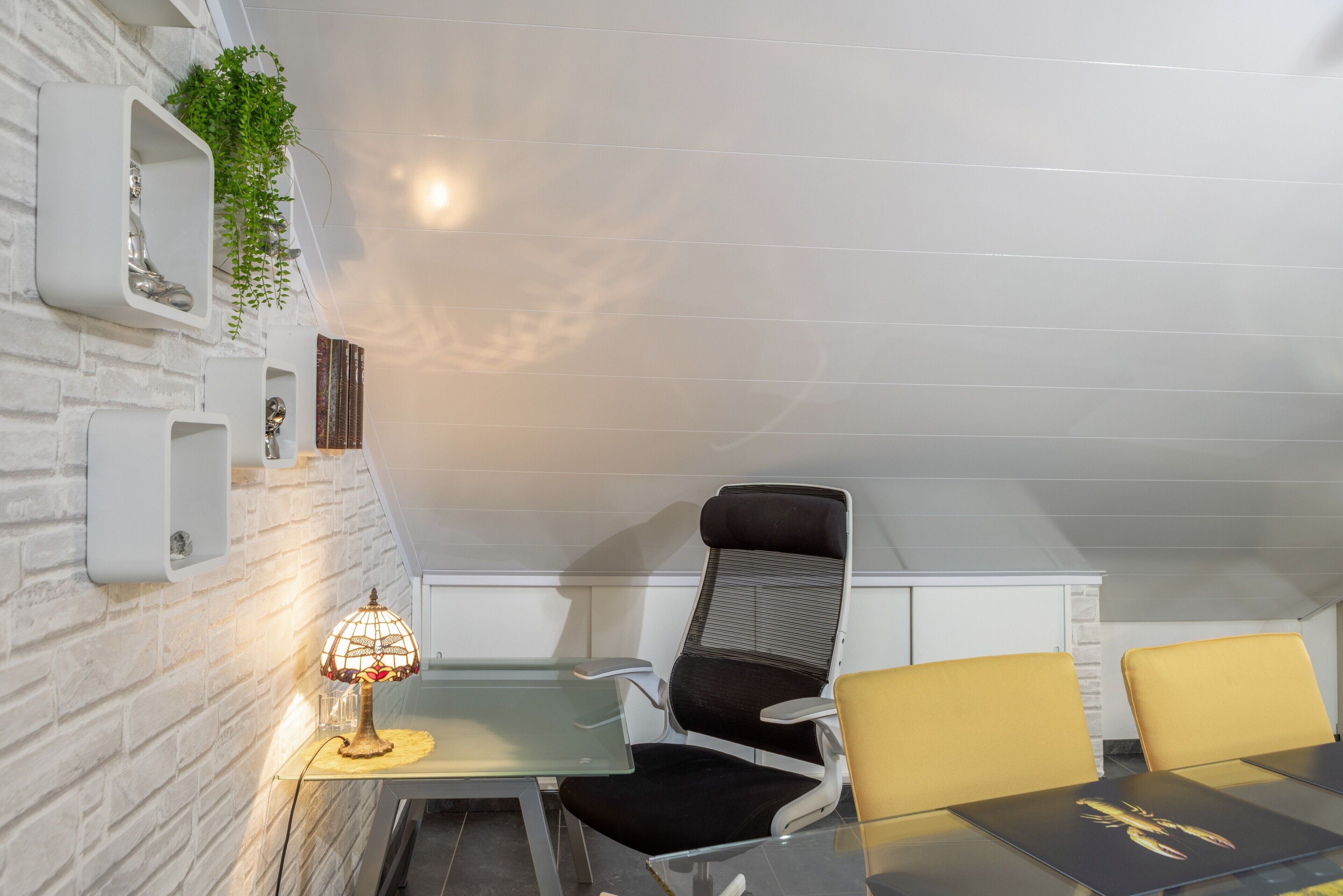 Ein stilvolles Zimmer mit Glastisch, zwei Stühlen, einer Lampe und einer Pflanze.